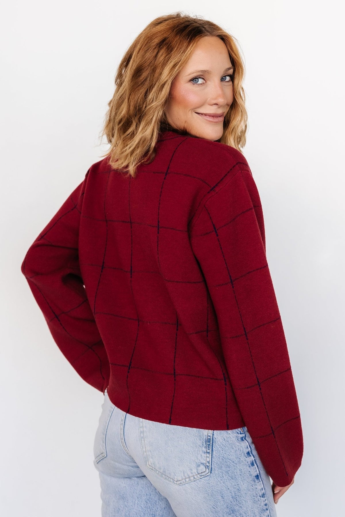 Close-up of the Remington Sweater knit and windowpane stitch in red and navy, highlighting the tight-knit construction and reversed inner color at the hem.