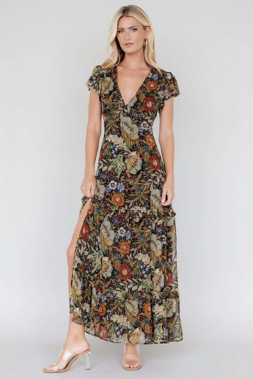 Front view of black chiffon maxi dress with green, orange and purple floral print, V-neck and tiered ruffle skirt.