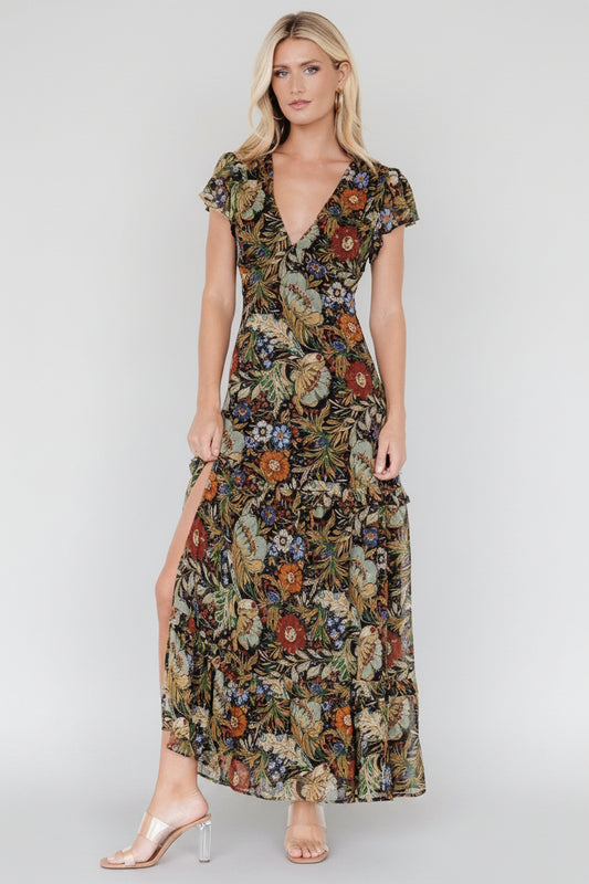 Front view of black chiffon maxi dress with green, orange and purple floral print, V-neck and tiered ruffle skirt.
