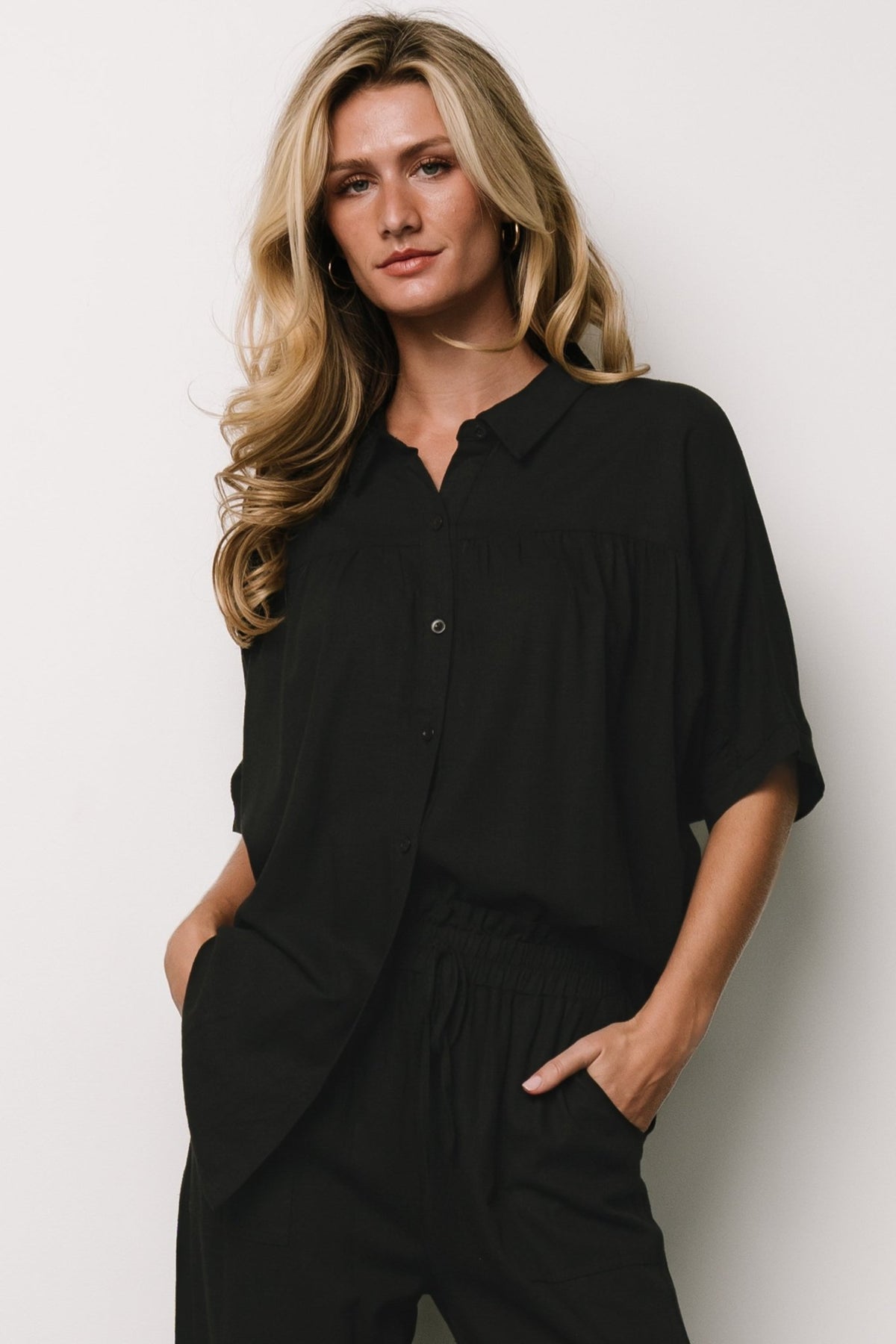 Back view of black Romy Button Top showing rounded hemline and relaxed dolman short sleeves in linen-blend fabric.