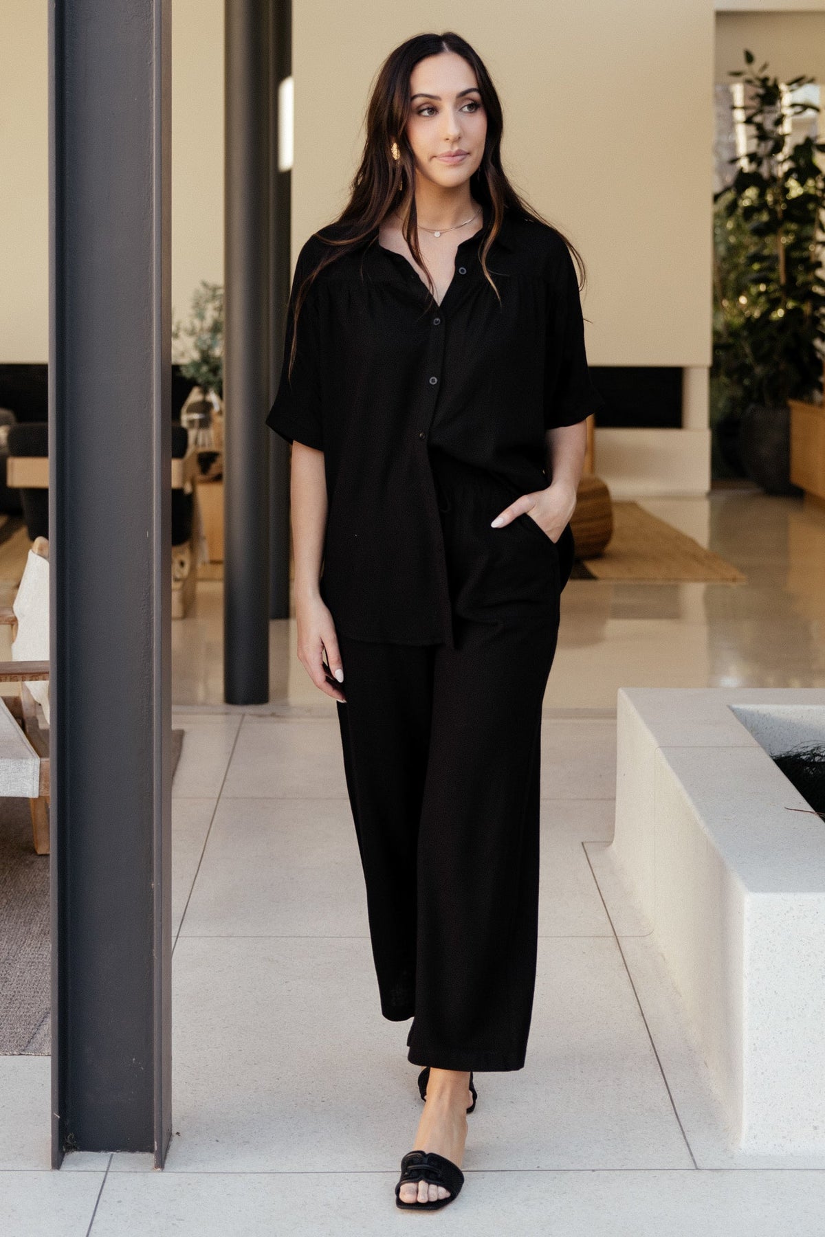 Back view of Romy black pants revealing wide leg shape and unlined construction for a breathable, easy-to-pack wardrobe staple.