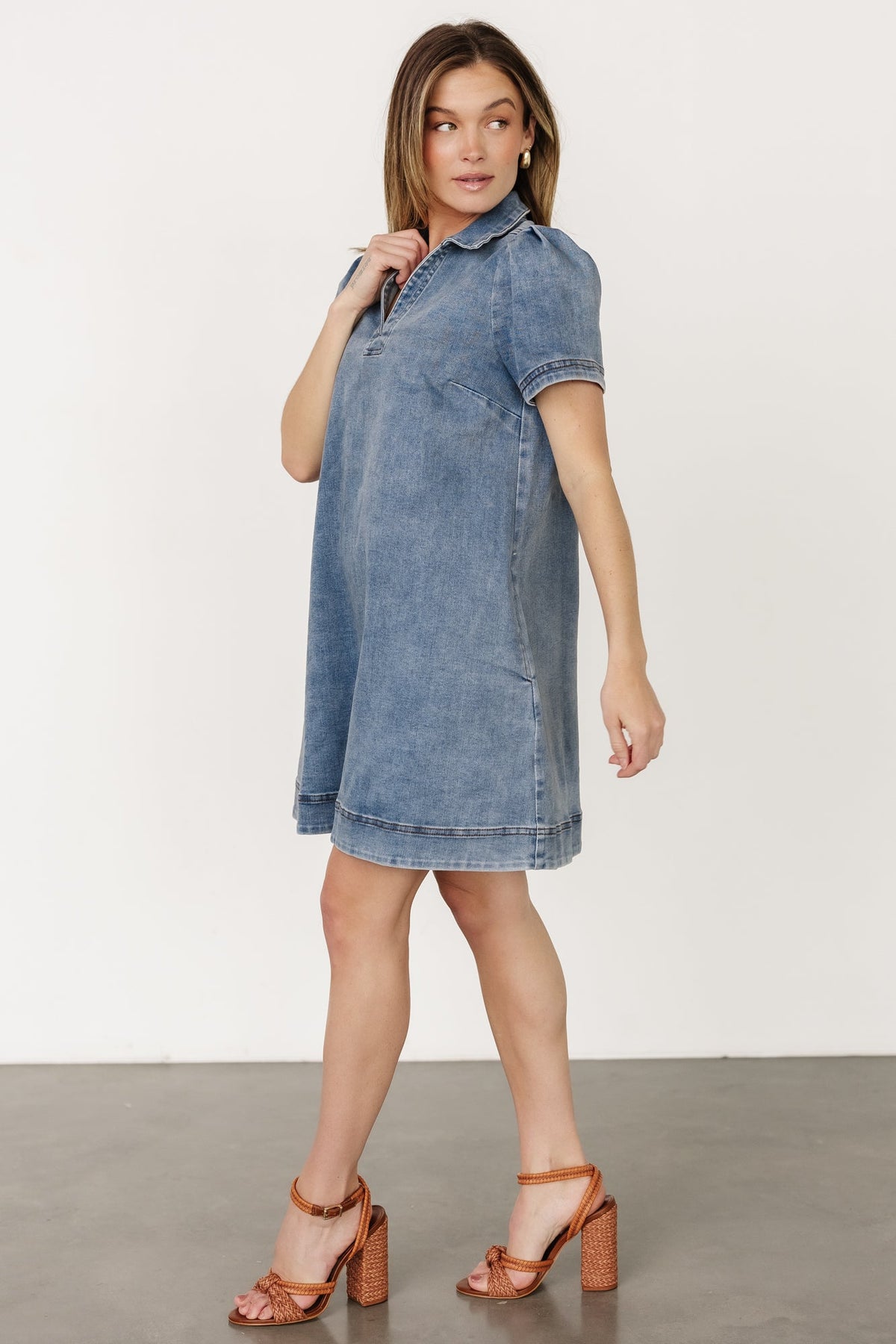 Side view of Saylor short denim dress demonstrating functional side pocket placement and relaxed silhouette on model.