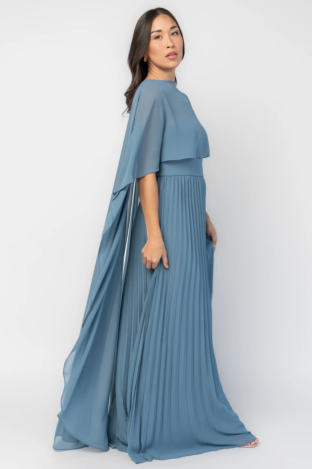 Serafina Strapless Gown in Blue with strapless neckline, removable sheer cape overlay, defined waist, and pleated skirt.