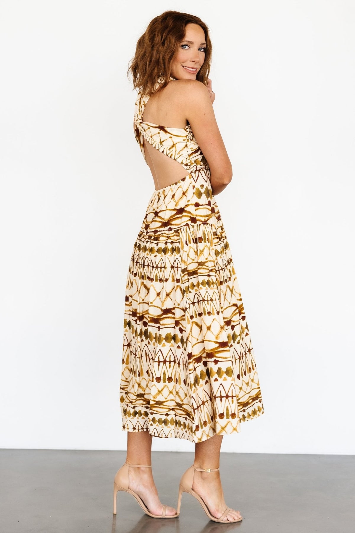 Detail shot of the dress pattern and sleeve crossover knot, highlighting tan and brown print tones and tailoring.