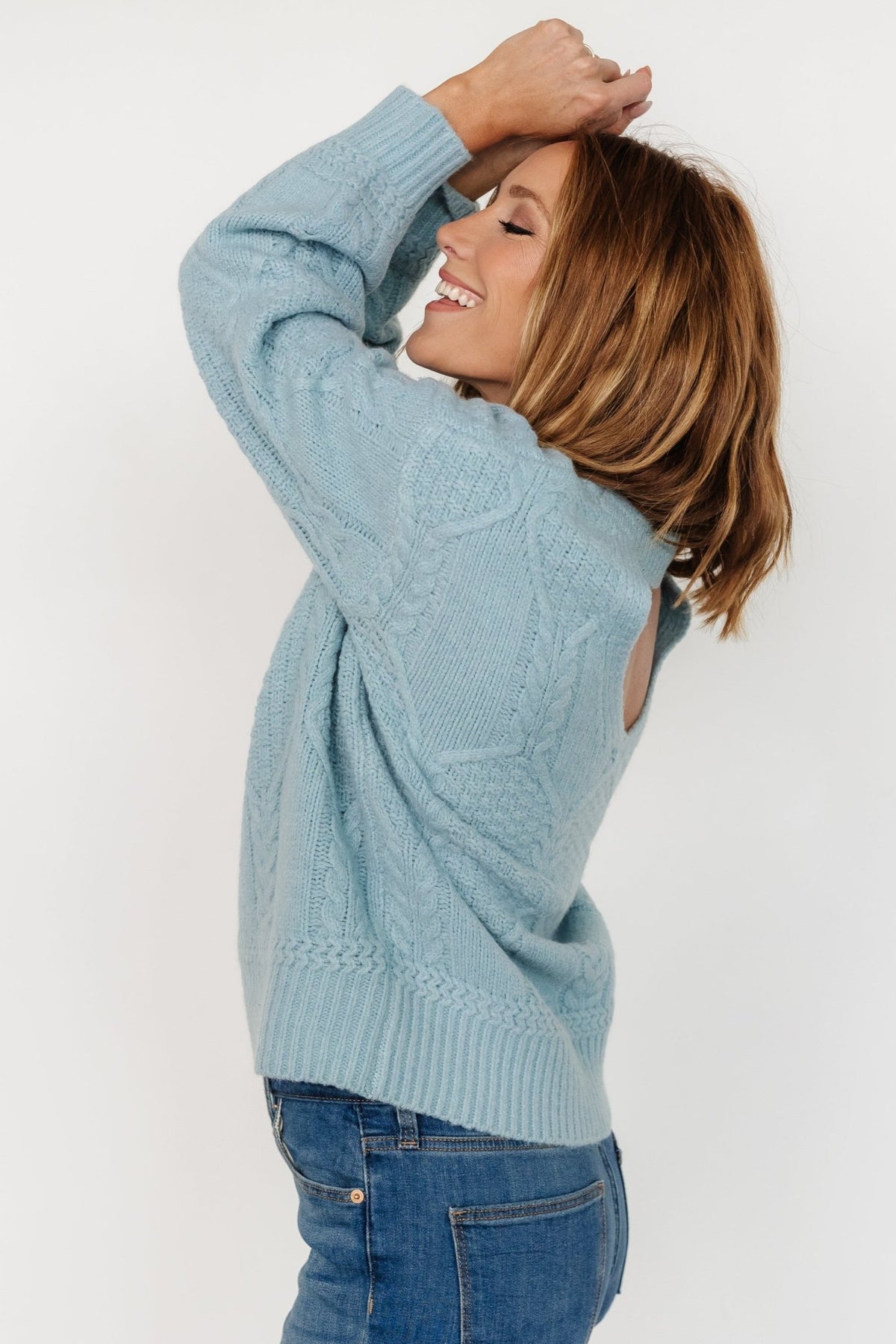 Back view of model in Sheffield sweater highlighting the partially open back detail and relaxed silhouette in light blue.