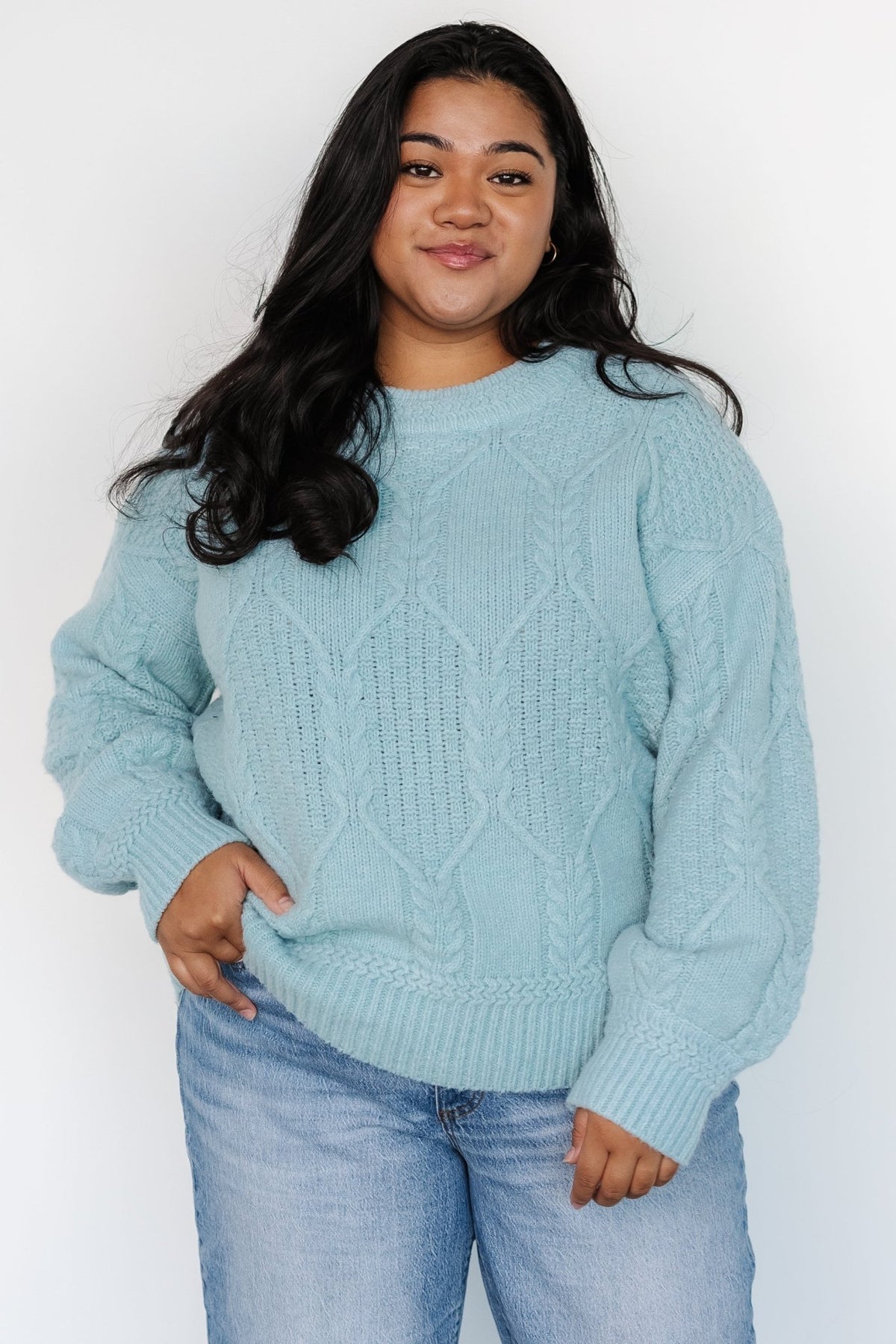 Close-up of cable knit texture and wide knit detail at the neckline on the Sheffield sweater in vintage light blue.