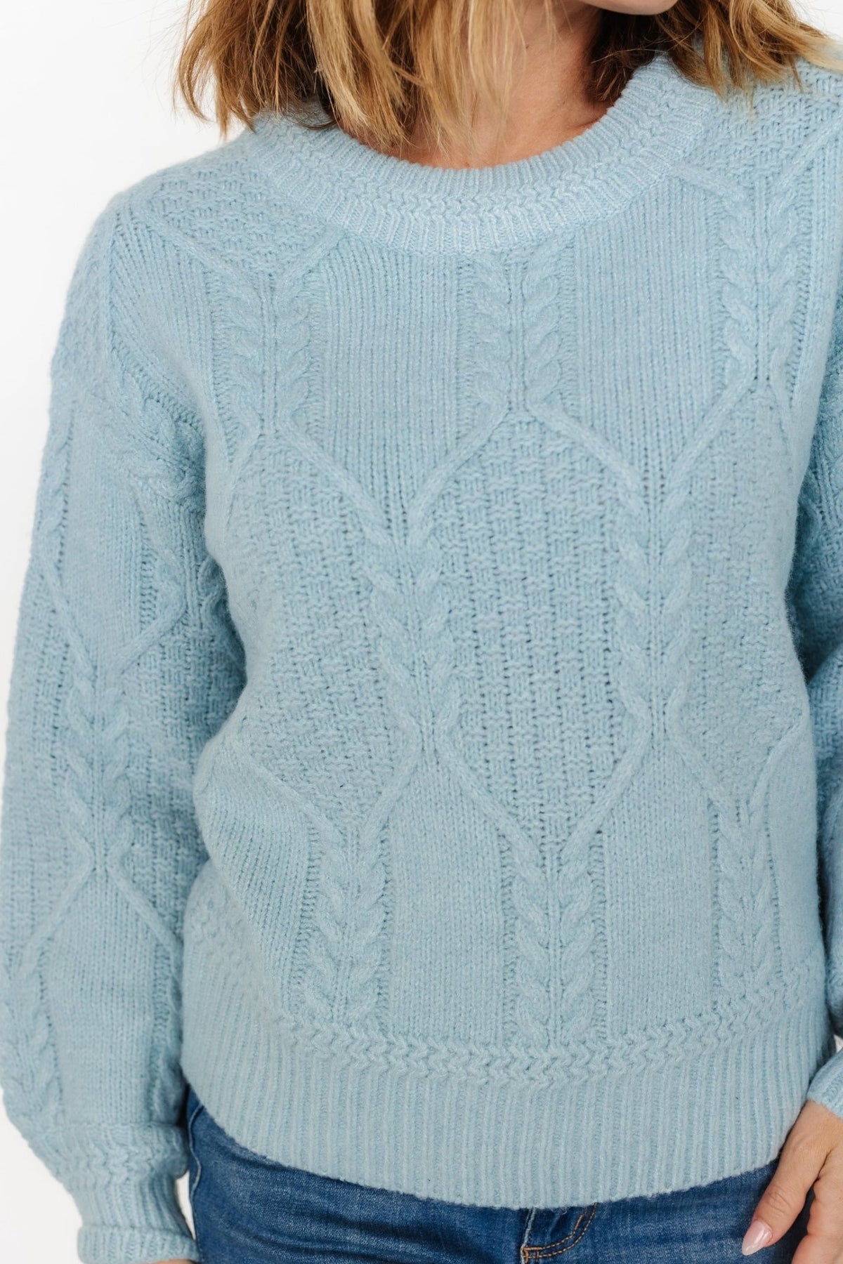 Lifestyle shot of Sheffield sweater in vintage light blue worn with skirt, showing relaxed silhouette and feminine open-back detail.
