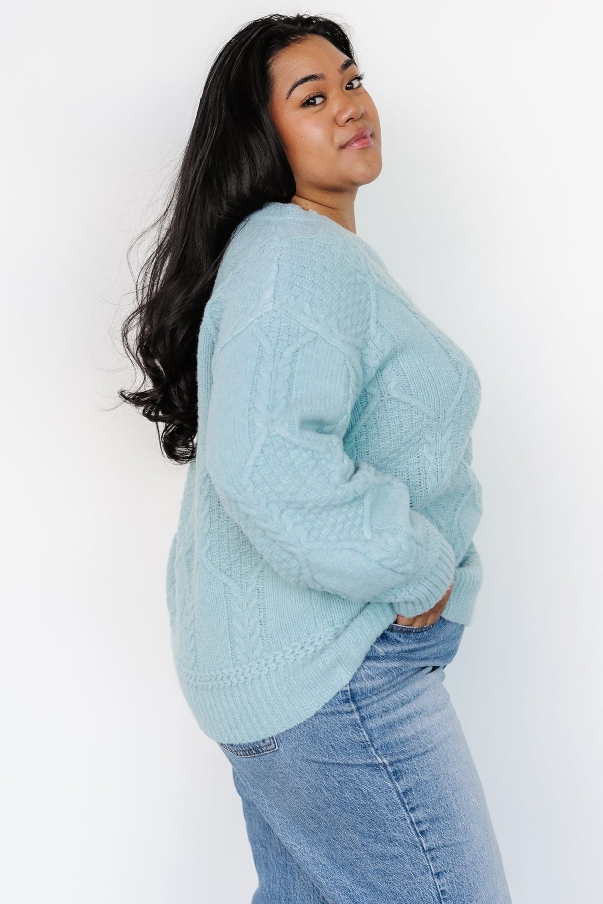 Side view of Sheffield cable-knit sweater in vintage light blue showing wide sleeve with knit cuff and dropped shoulder.