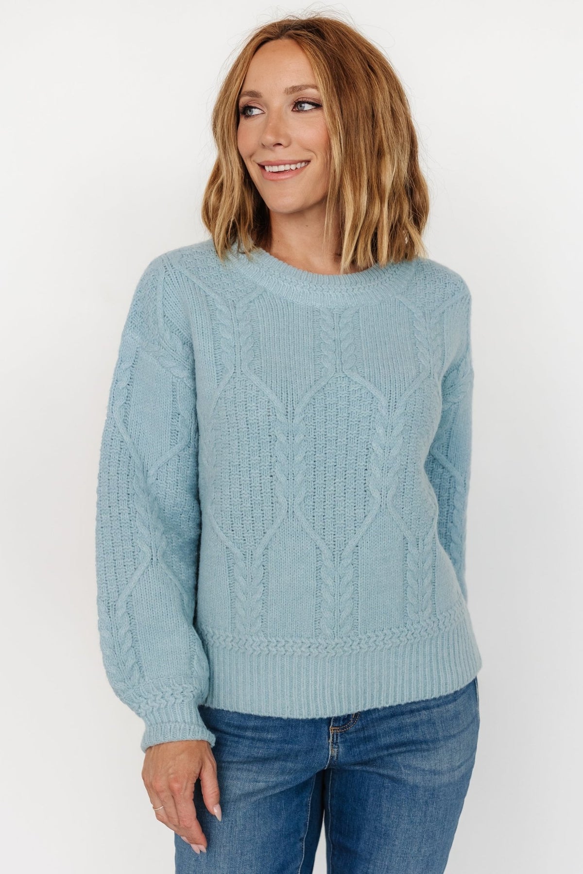 Model styling the Sheffield sweater with denim, showing relaxed fit, dropped shoulder, and open-back feature in light blue.