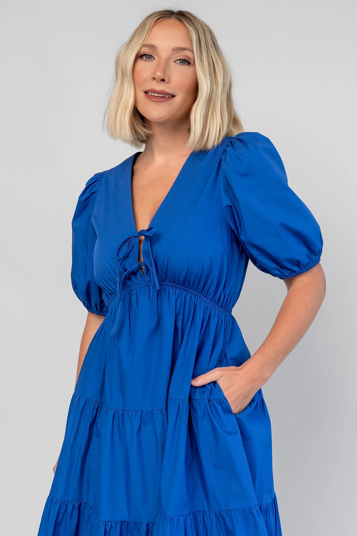 Sheila Tiered Midi Dress in Cobalt with V-neckline, front ties, puff sleeves, smocked empire waist, and tiered skirt.