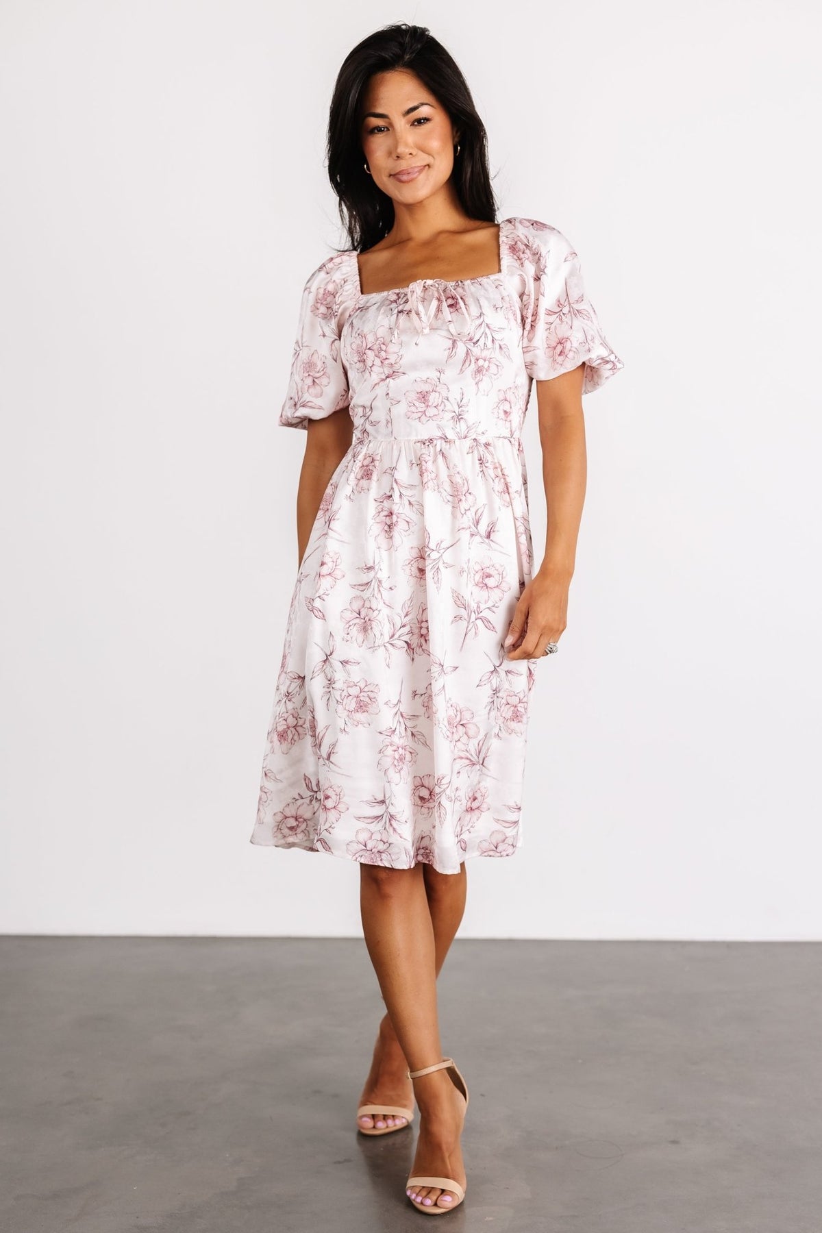 Front view of Sonnet Short Dress in blush floral print on model, showing square neckline, faux tie, short puff sleeves and A-line skirt movement.
