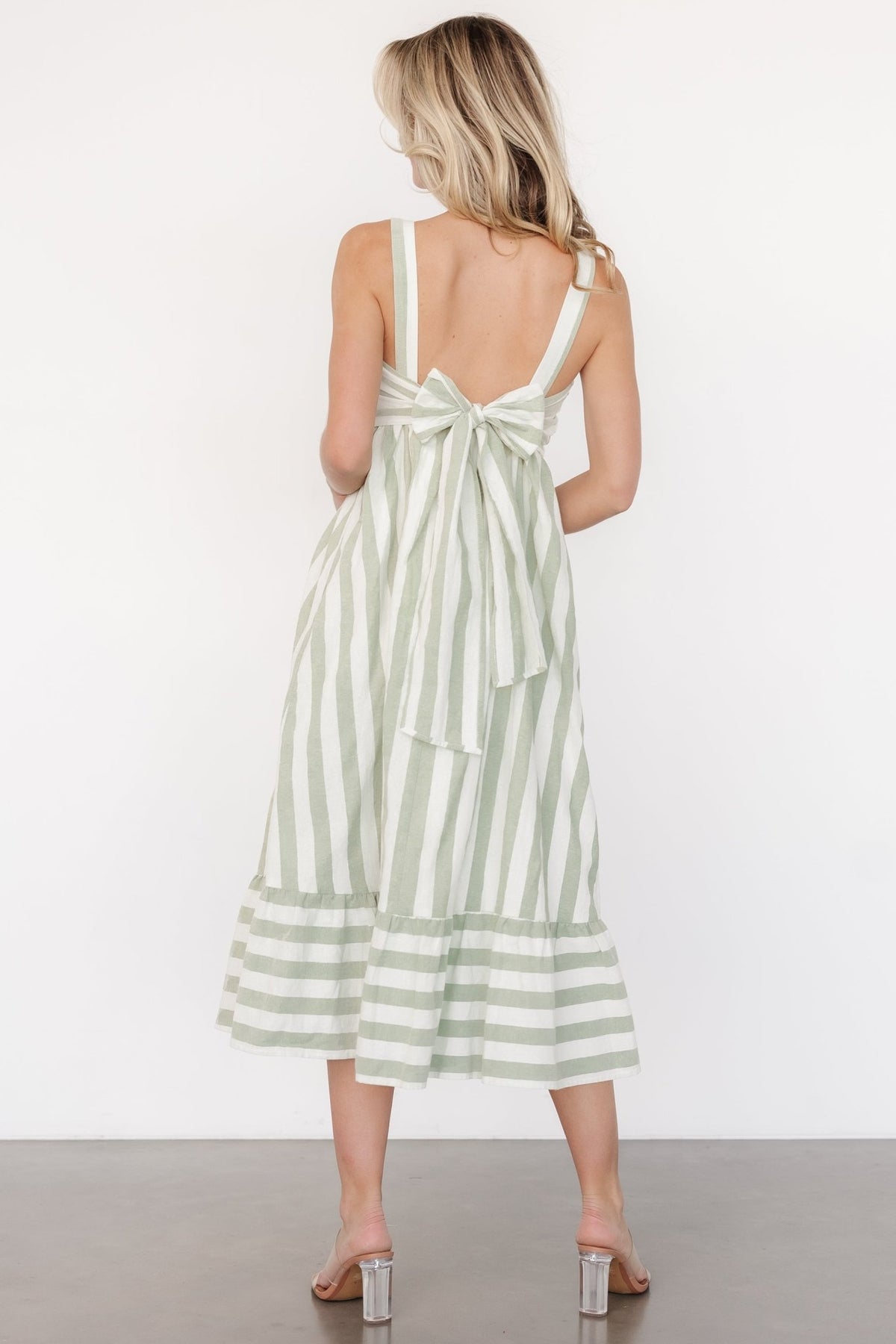 Side view of Soren midi dress showing hidden side pocket and single tiered skirt in heather sage and cream stripes.