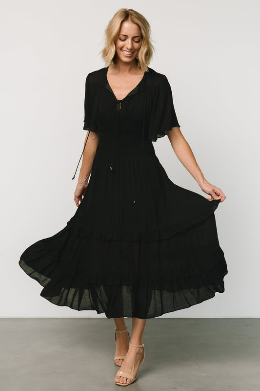 Front view of a model wearing a black boho midi dress with V-neckline, smocked waist and a fully lined midi skirt for smooth drape.