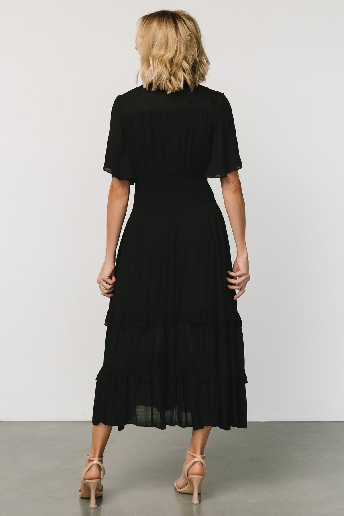 Detail shot showing the smocked waist and seamwork on the dress, illustrating the gathered texture that defines the waistline.