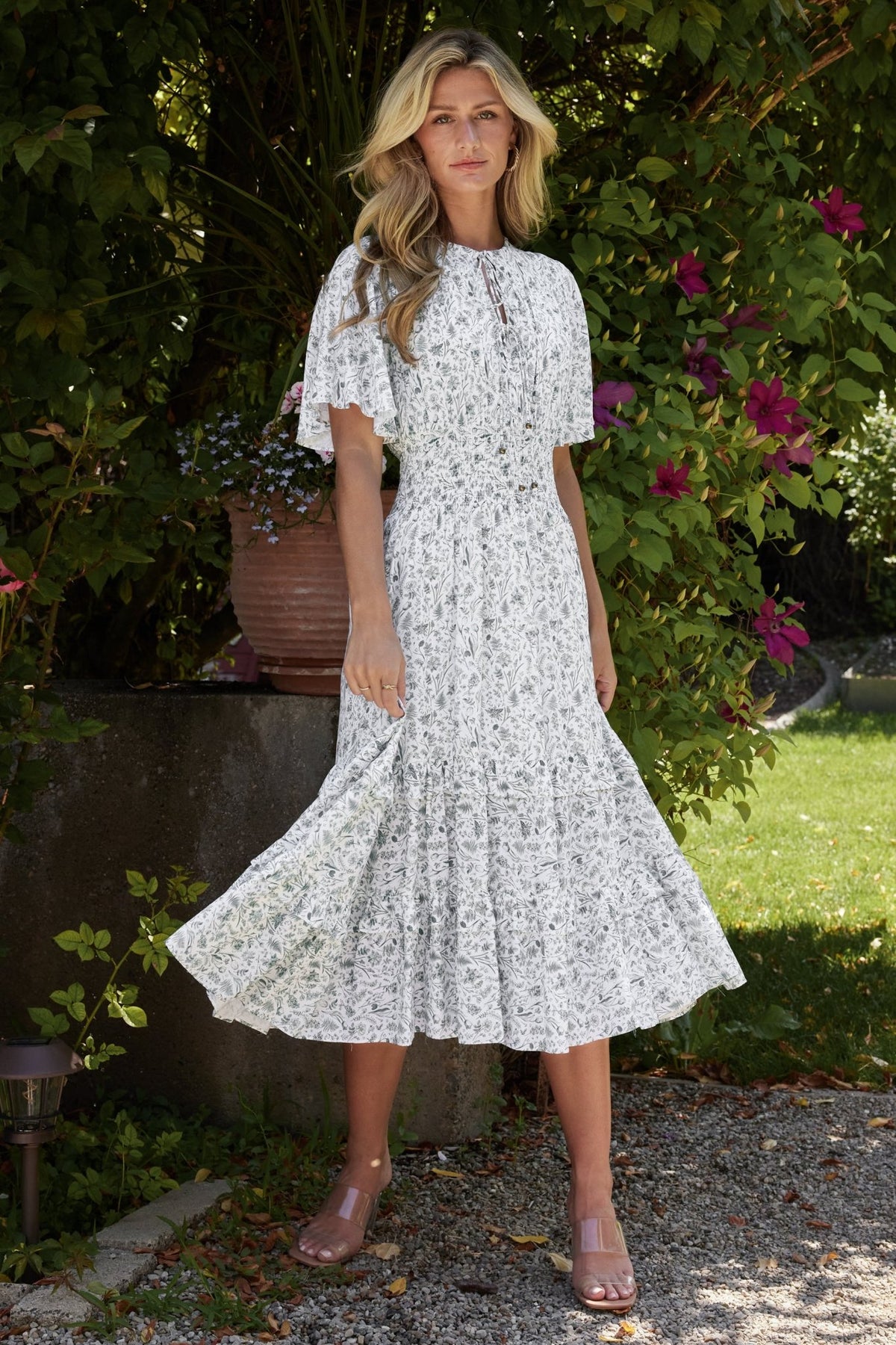 Back view of white and sage floral midi dress highlighting skirt length, seam lines, and balanced print placement.