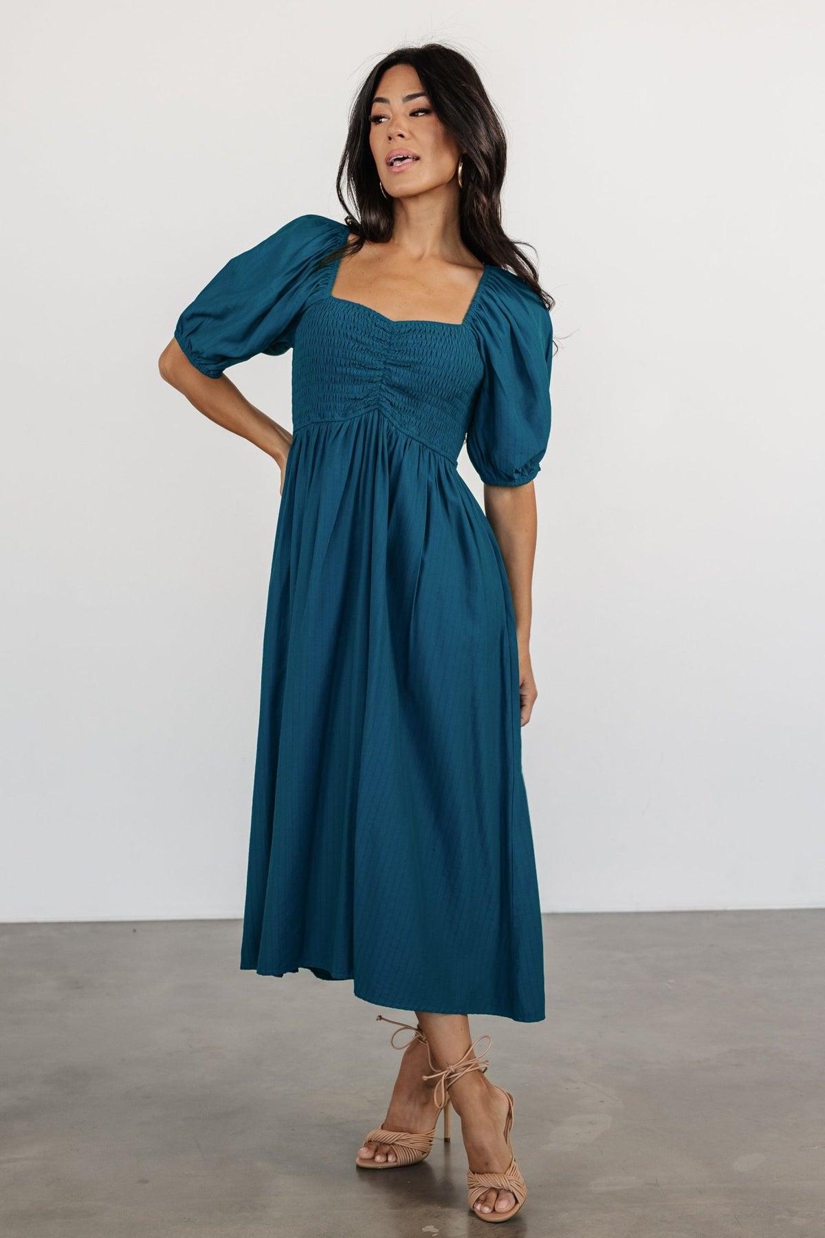 Front view of Stefania Midi Dress in Mediterranean Blue on a model; smocked bodice, sweetheart neckline, midi A-line skirt and hidden pockets visible.