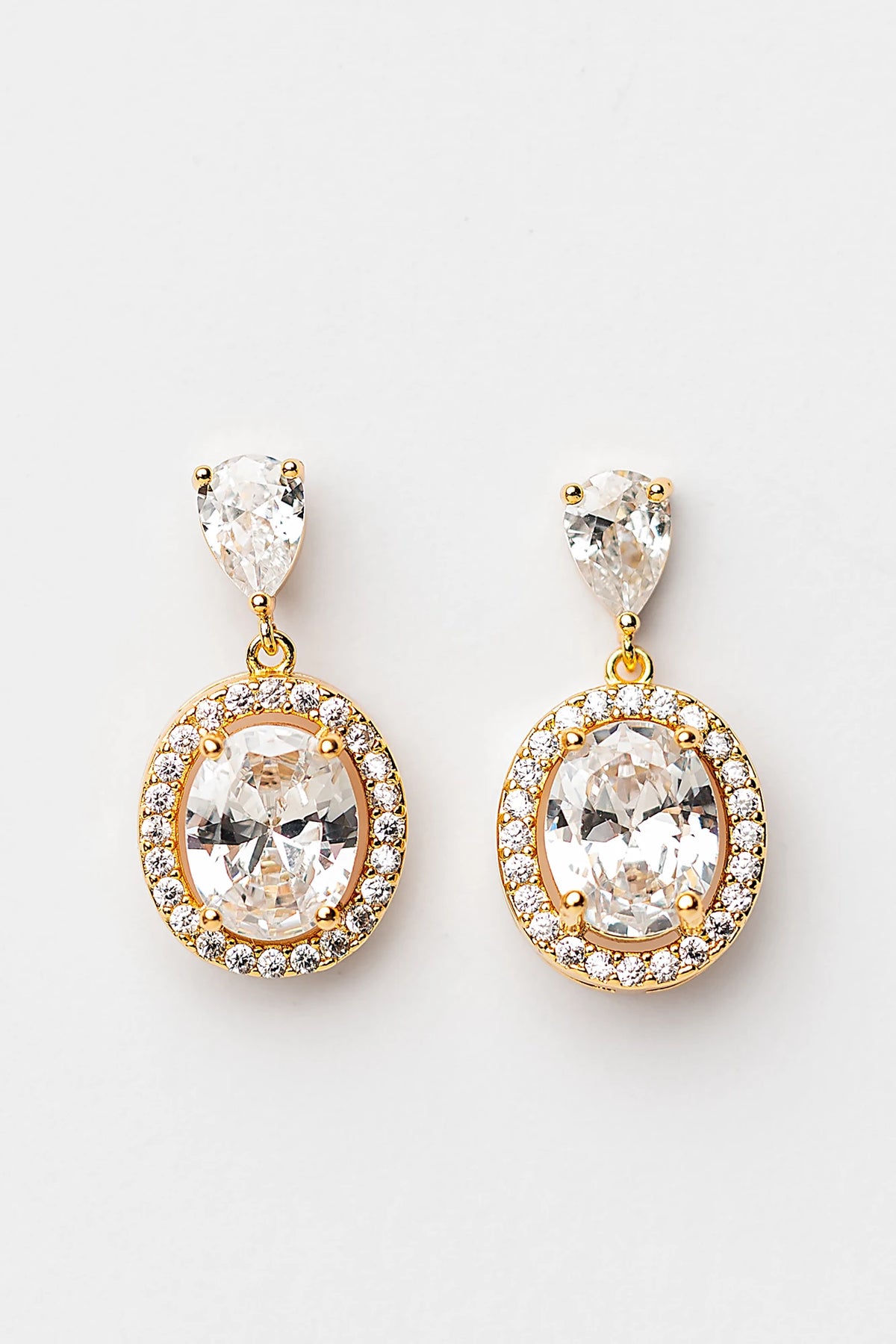 Stena Oval Dangle Drop Earrings in Gold with oval center stone and pavé stone border.