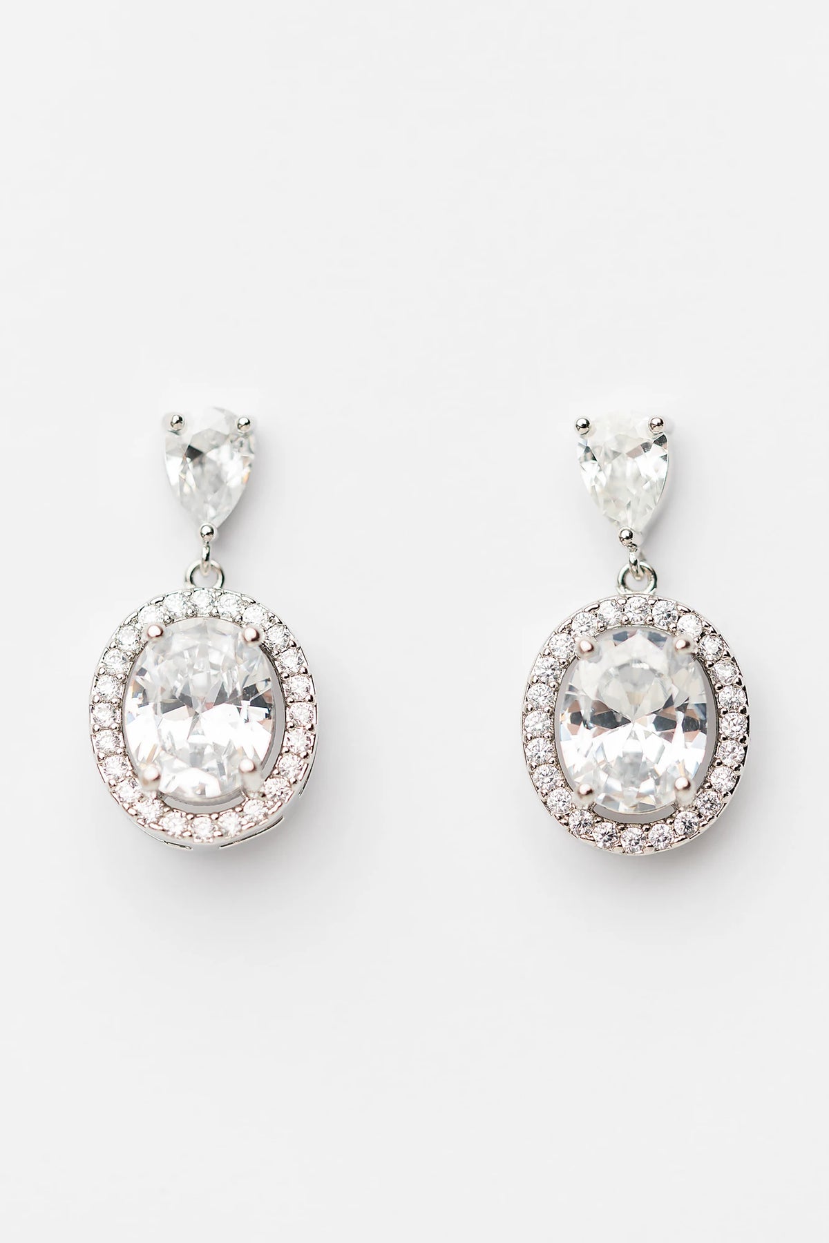 Stena Oval Dangle Drop Earrings in Silver with oval center stone and pavé stone border.