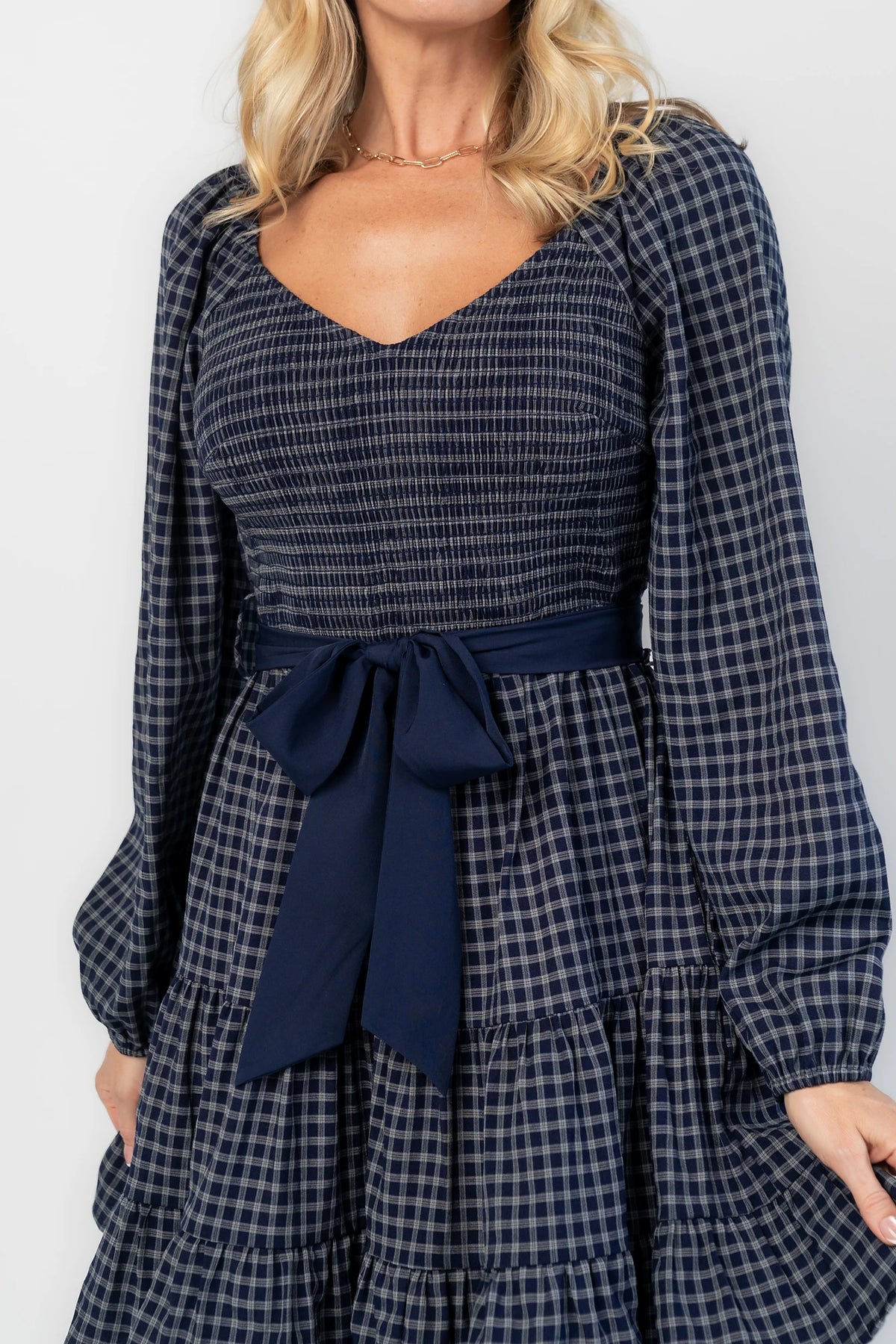 Stina Short Dress in Navy Plaid with smocked V-neck bodice, long sleeves, and tiered skirt.