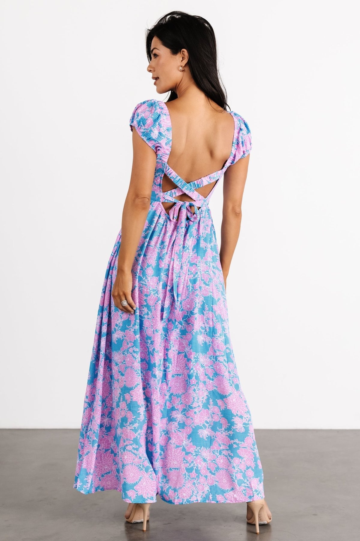 Three-quarter view of the blue and pink Tabitha maxi highlighting the elastic cross-back, tie detail, and flowing skirt movement.