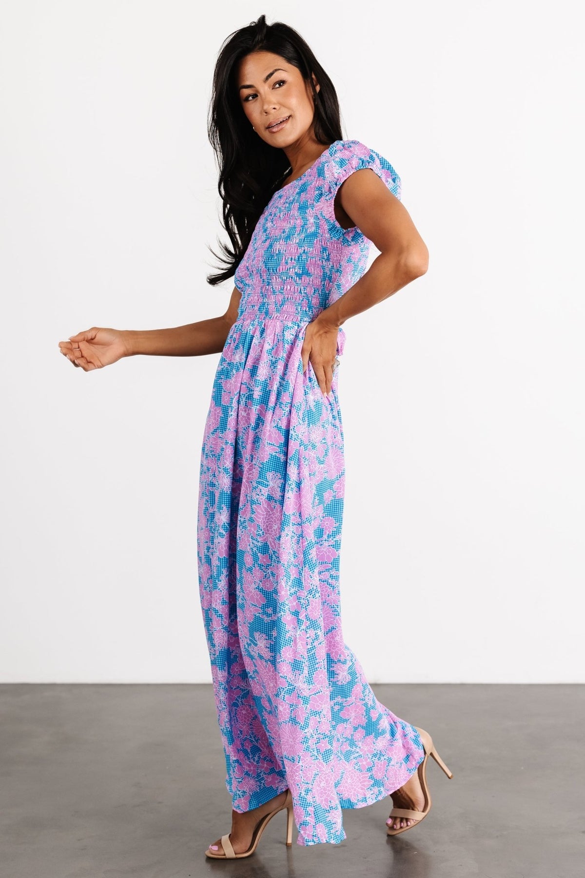Close-up of smocked bodice and short puff sleeve with elastic cuff on the Tabitha maxi in blue gingham and pink floral accents.