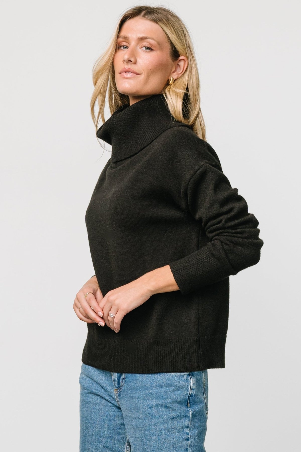 Close-up of wide knit cowl neck and ribbed collar on black turtleneck sweater, showing stitch texture and neat finish.