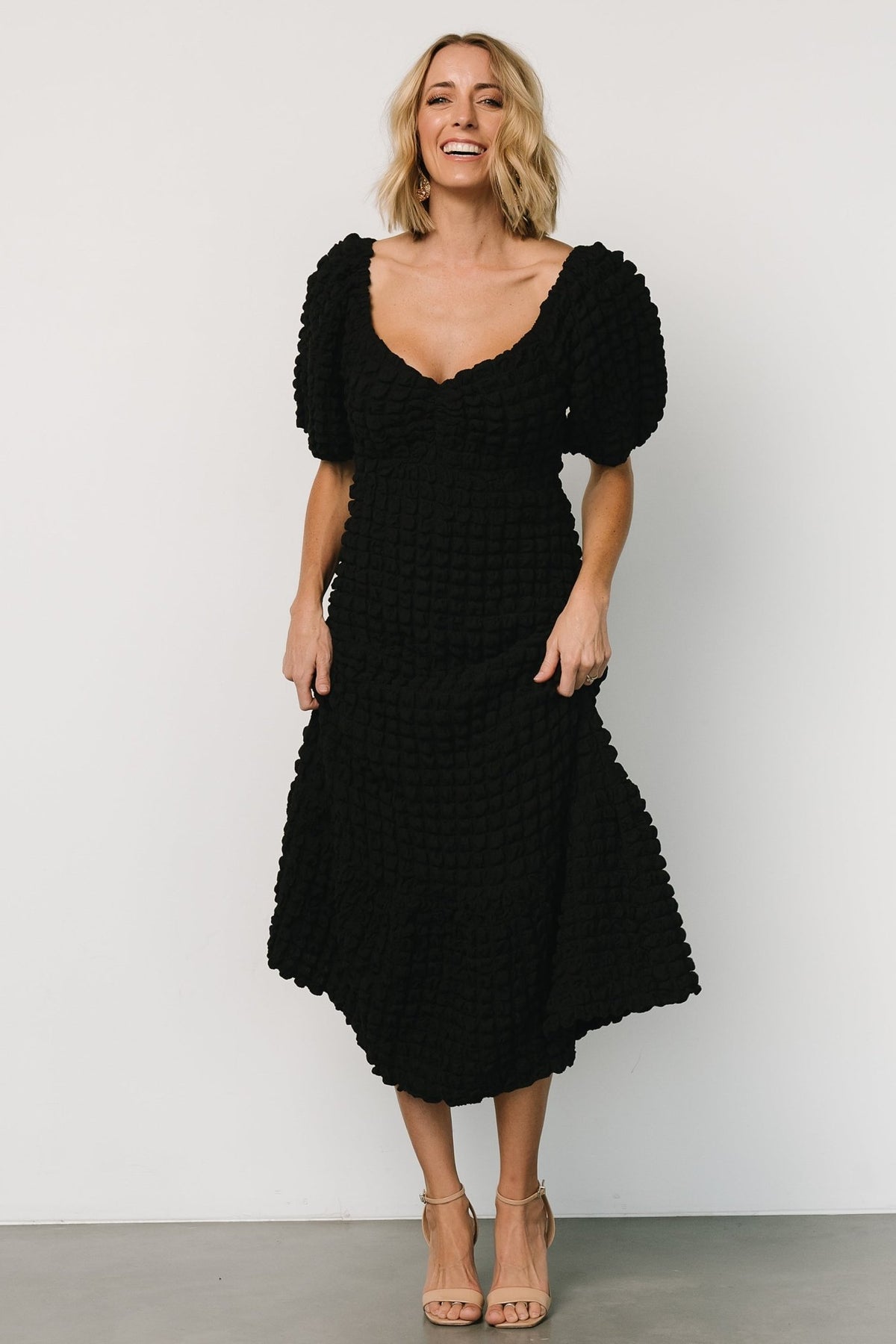 Back view of the Therese midi dress in black highlighting the fitted hip and single bottom tier that creates a trumpet silhouette.