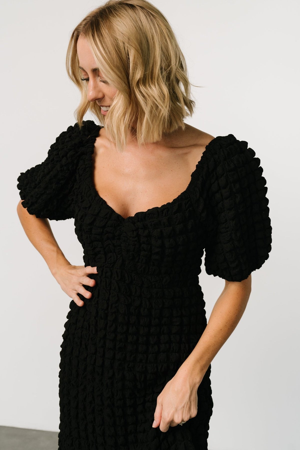 Full-length on-model shot of the black Therese dress showing puffed sleeves, elastic upturned empire waist, and subtle trumpet hem.