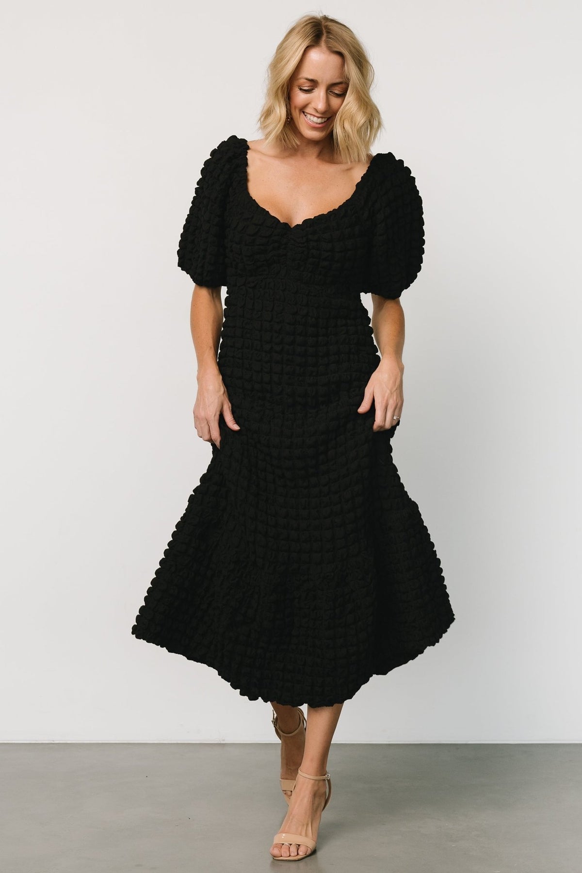 Detail of the puffed sleeve with elastic cuff and the center-gathered bust on the Therese black midi dress.