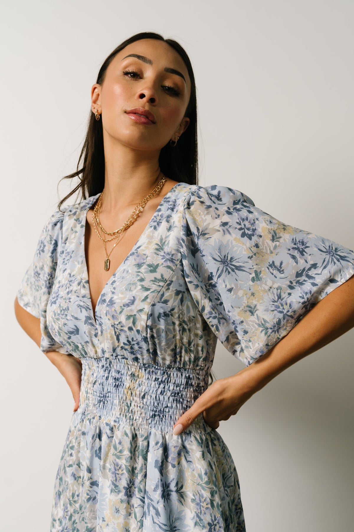 Model walking in the white and blue Verona Smocked Maxi Dress, illustrating skirt movement and the dress's flattering smocked waistline.