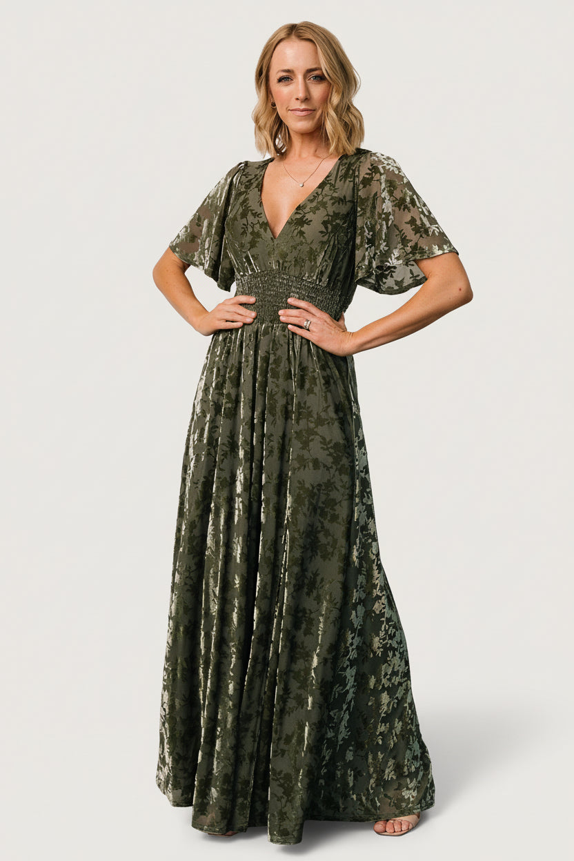 Full-length front view of Veronica Velvet Maxi Dress in dark sage on a model, showing deep V-neck, smocked waist, and left leg slit.