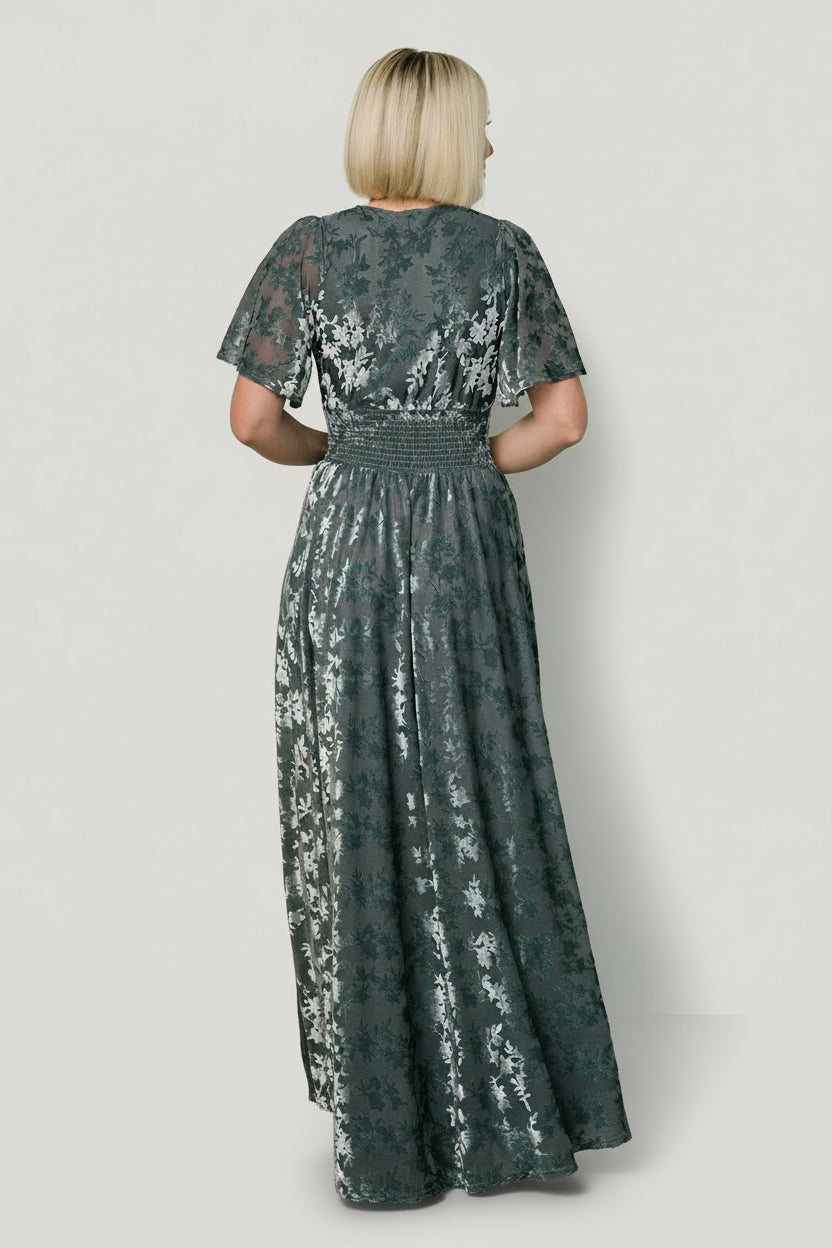 Back view of Veronica velvet maxi dress in slate blue showing smooth lined back, gentle sheen of embossed velvet, and relaxed skirt silhouette.