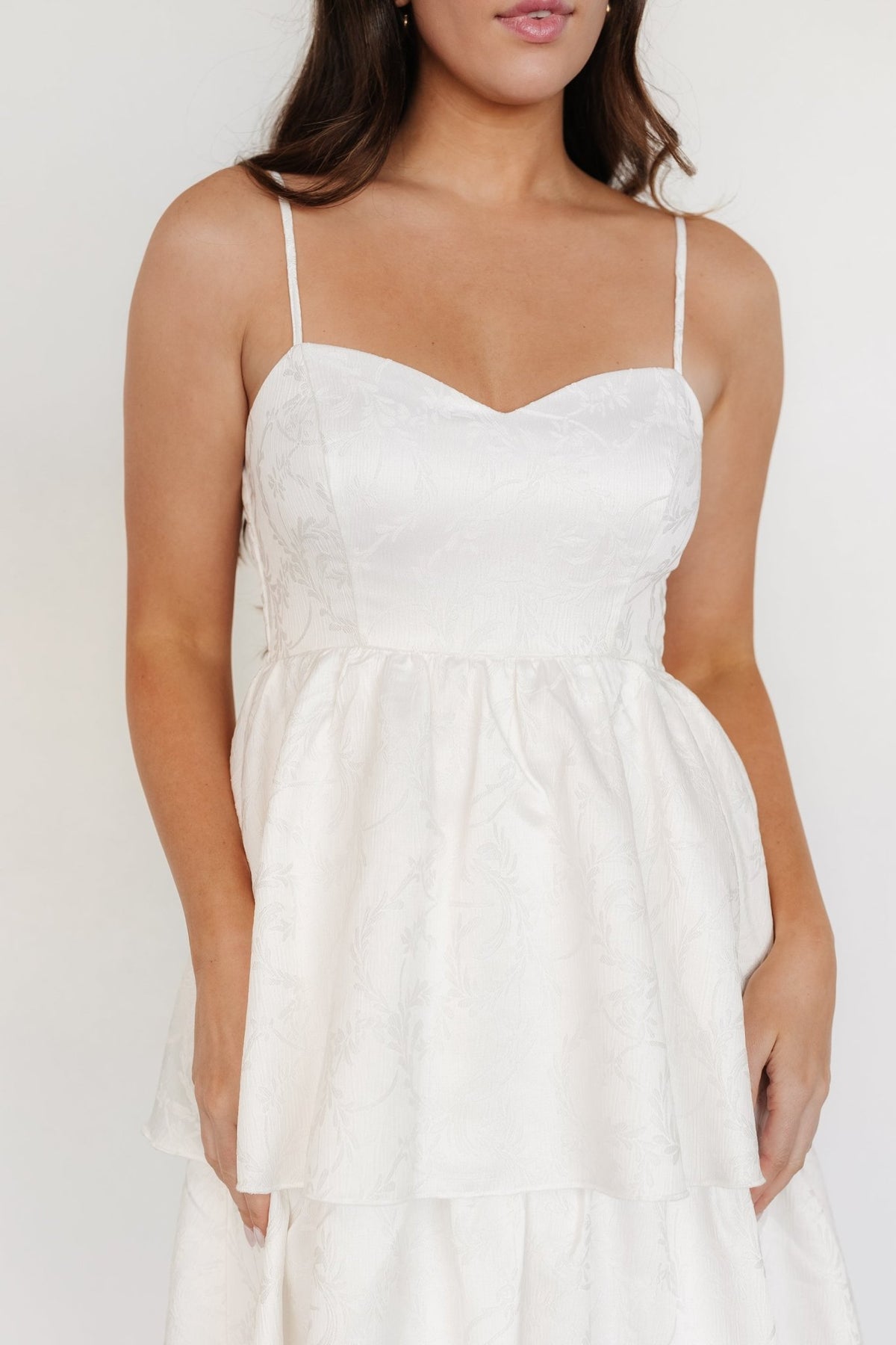 Full-length shot of off-white tiered dress on model, displaying three overlapping tiers and flowing maxi silhouette.