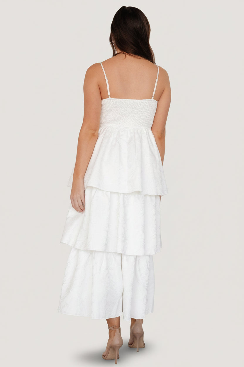 Side view of the embossed tiered dress showing sleeve-less profile, smooth lining, and gentle volume at the hem.