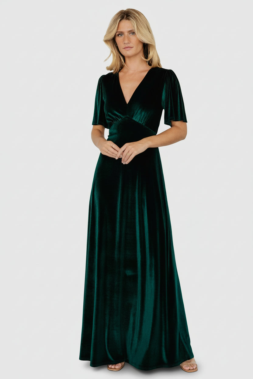 Front full-length view of emerald velvet Vivian maxi dress with deep V-neck, flutter sleeves, gathered empire waist, and flowing gown-length skirt.