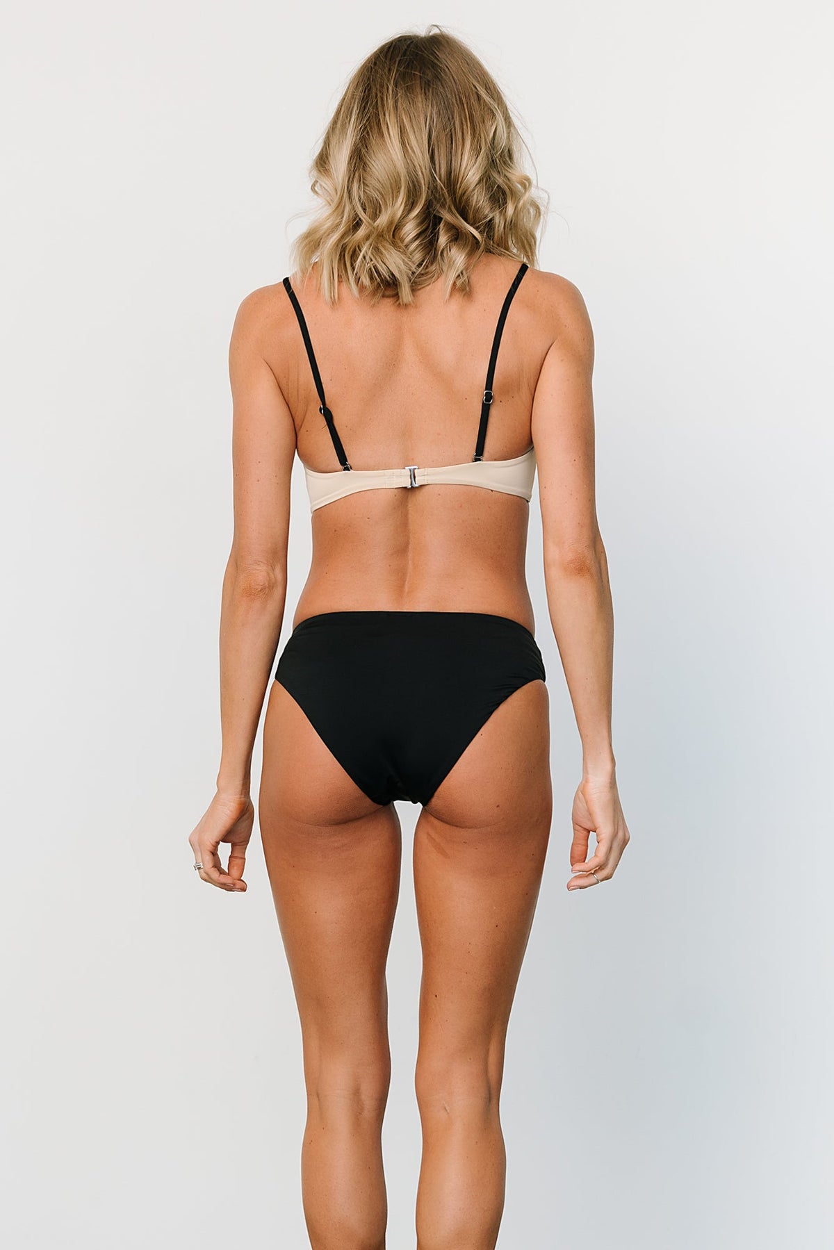Side close-up of Vixen bikini bottom in black and sand showing stretch fabric, seam detail, and moderate coverage fit.
