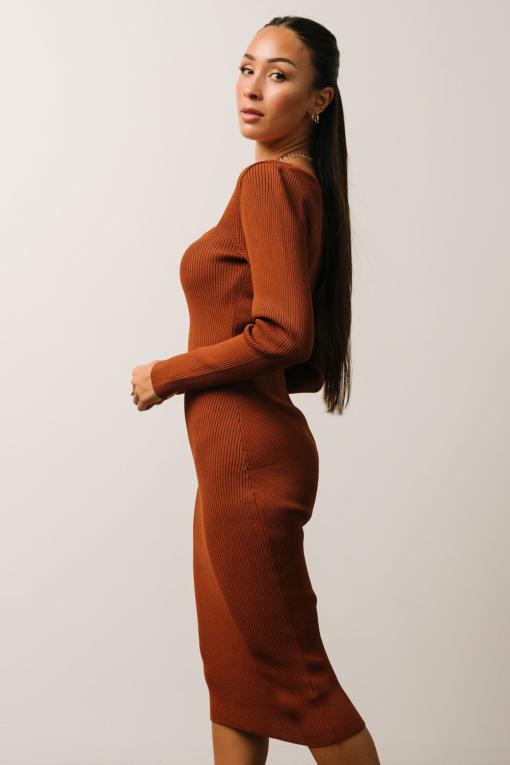Back view of chestnut ribbed midi dress on model showing midi hemline and contoured seam lines that maintain a sculpted, elegant fit.
