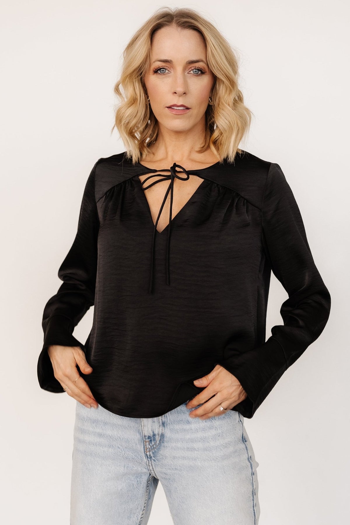 Sleeve detail of black Westminster Satin Top showing long sleeve silhouette and bell cuff with textured satin-like fabric.