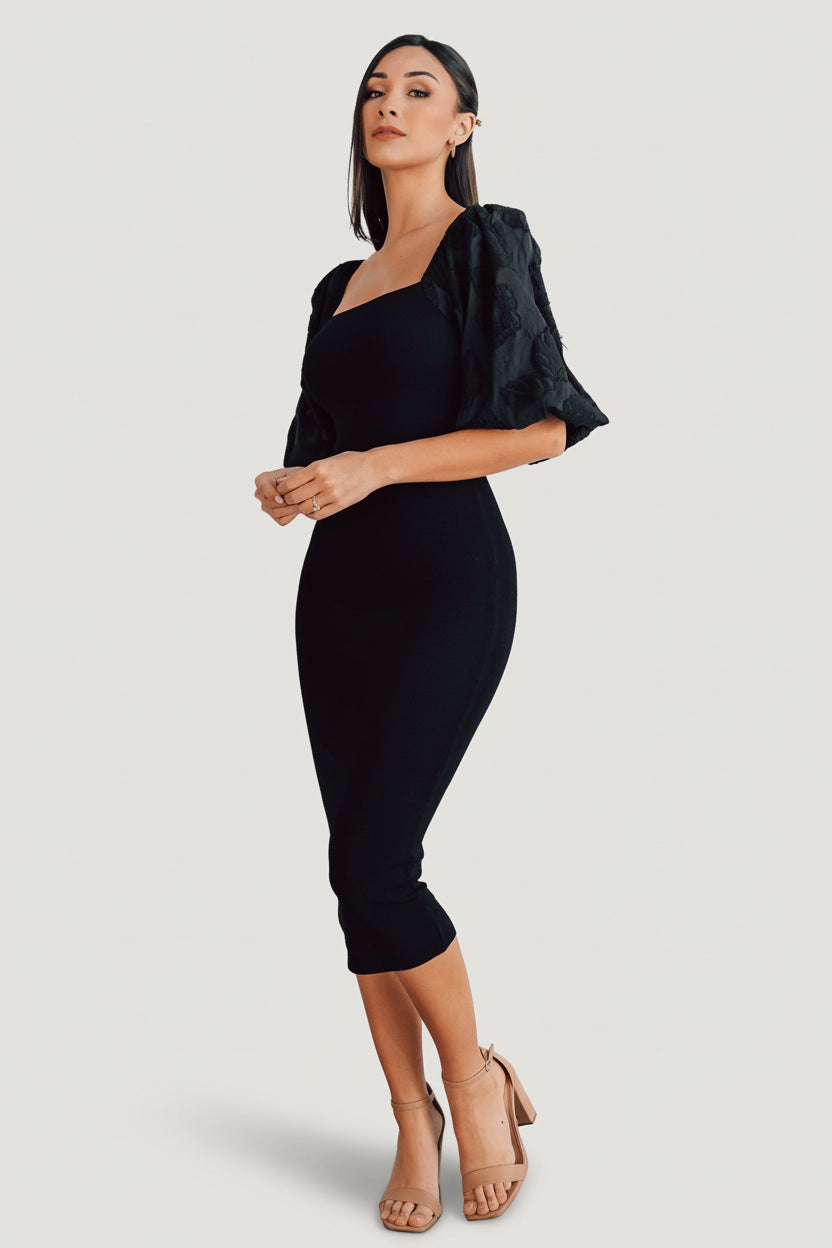 Styled flat-lay of the Weyland bodycon midi dress in black, emphasizing square neckline, embossed sleeve texture, and midi length.