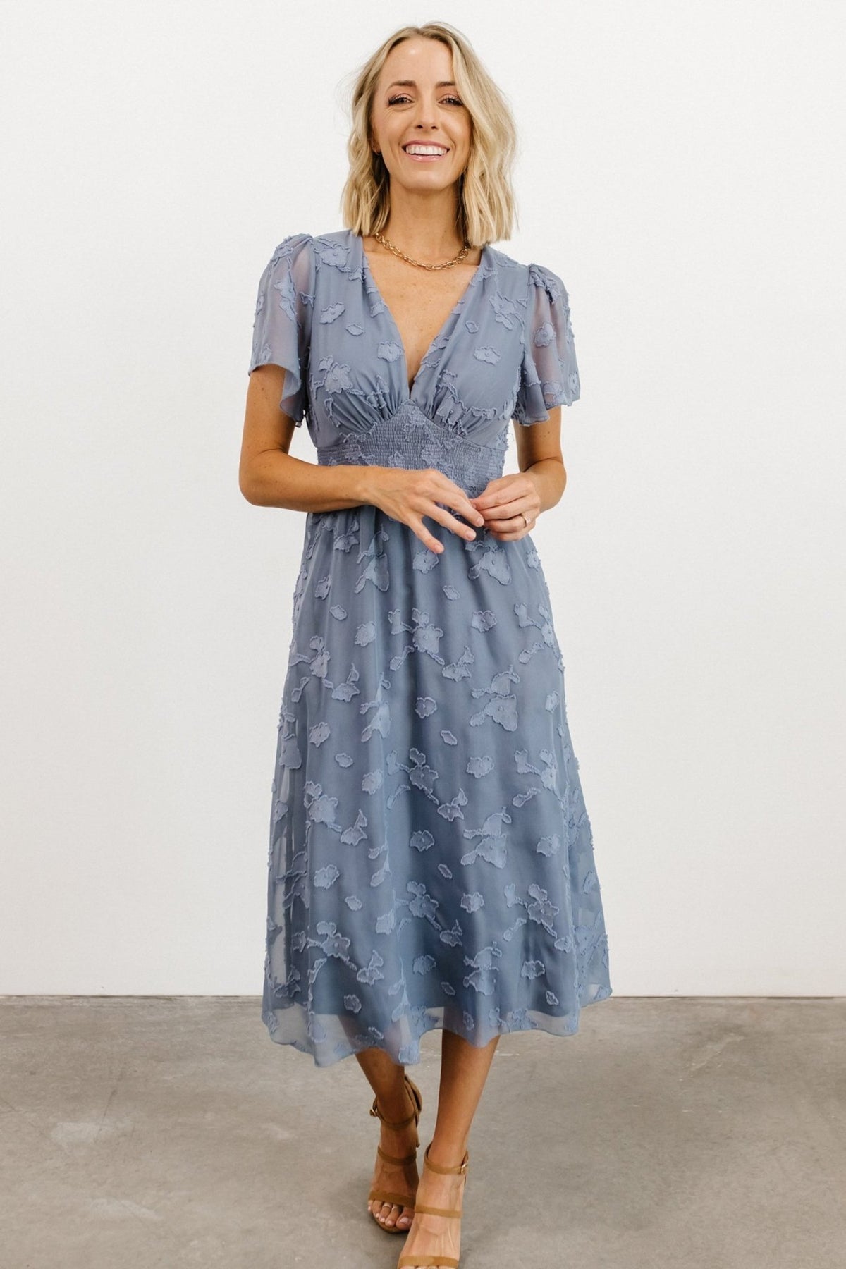 Full-length studio shot of the blue floral chiffon midi dress showing silhouette, sleeve length, and natural movement of the skirt.