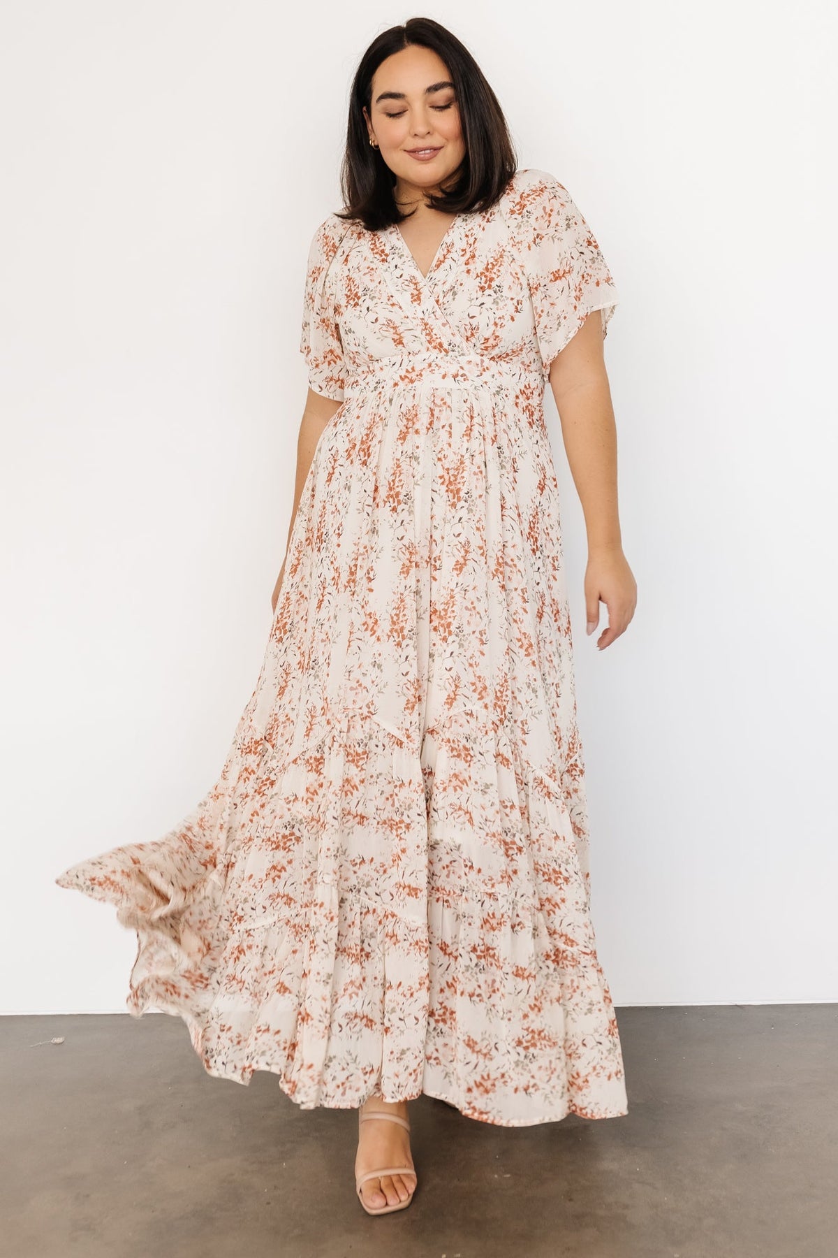 Close-up of surplice neckline and flutter sleeve detail on cream and rust floral chiffon fabric with soft pleating.