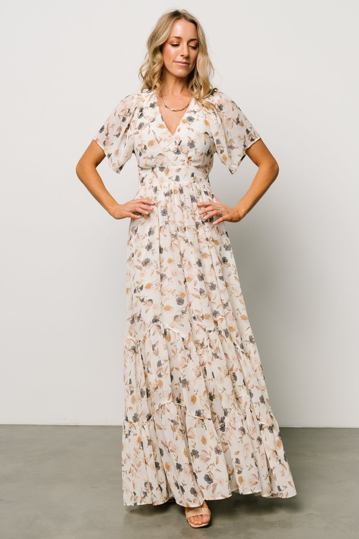 Close-up of sleeve and bodice showing flutter sleeve edge, surplice seam, and delicate floral pattern.
