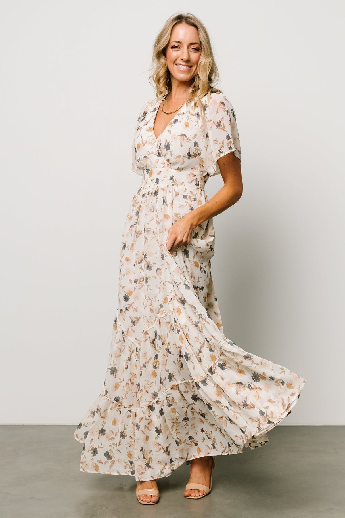 Three-quarter view of Katherine maxi dress in cream multi floral showing angled tiered skirt and soft movement.