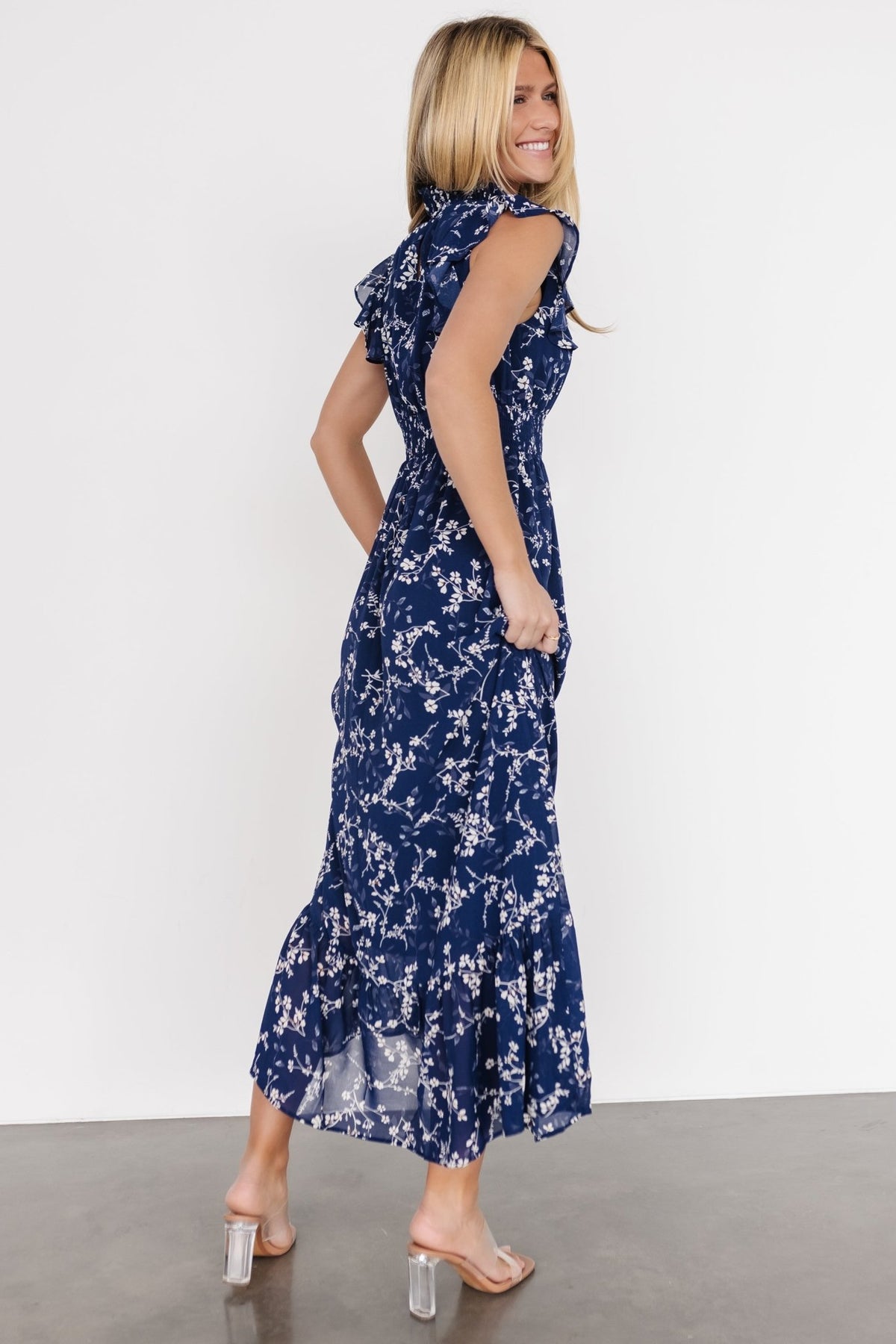 Back view showing button closures at the neck and the gentle sweep of the lined chiffon skirt in a blue and white floral print.