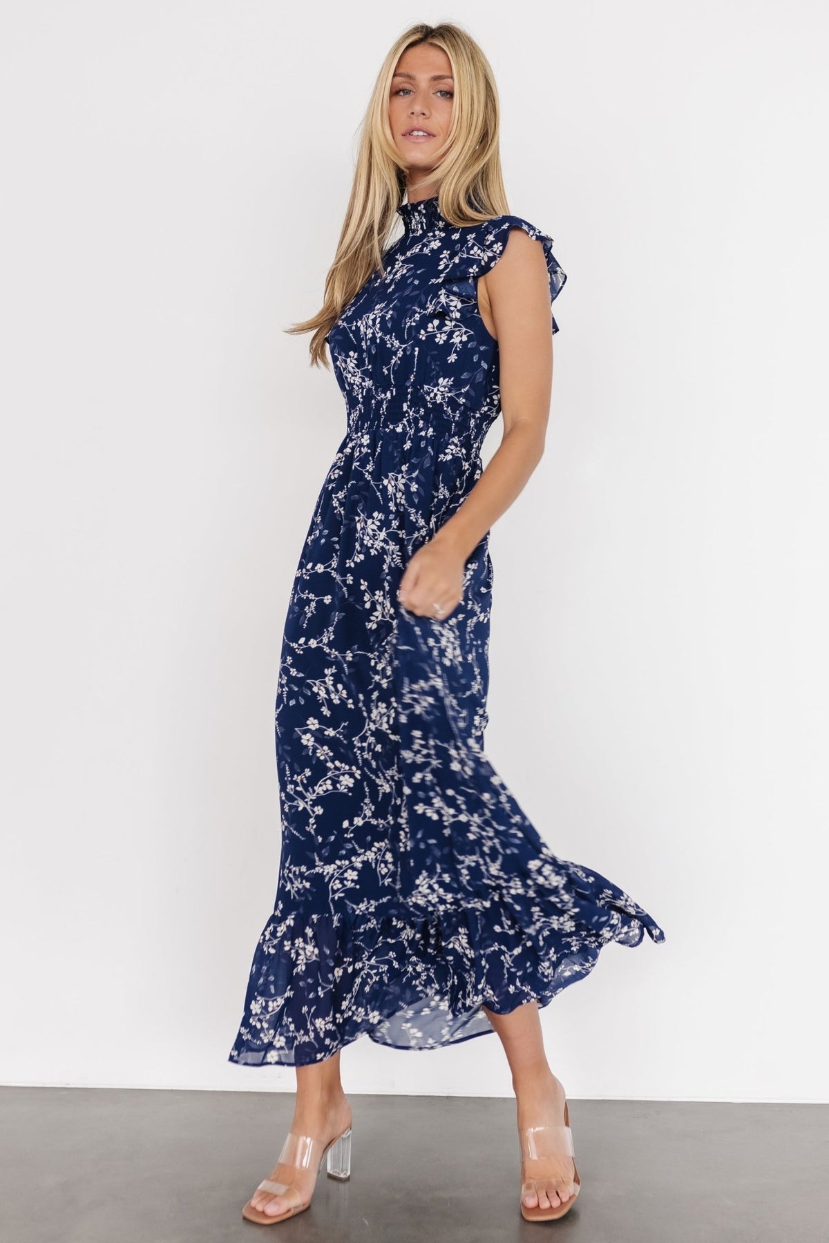 Lifestyle image of the blue floral chiffon maxi dress styled for a garden or resort look, highlighting ruffle details and soft fabric.