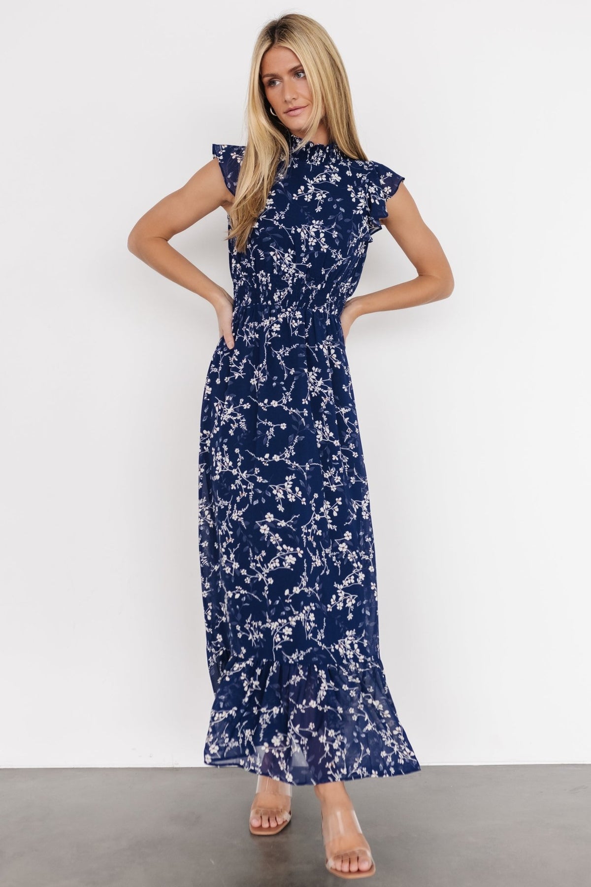 Close-up of smocked high neckline and back button closures on the blue floral chiffon dress, showing texture and stitching detail.