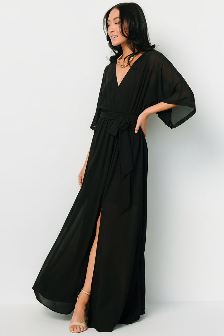 Close-up of crossover surplice neckline and bodice of the Kia Kimono Maxi Dress in black showing fabric texture and seam details.