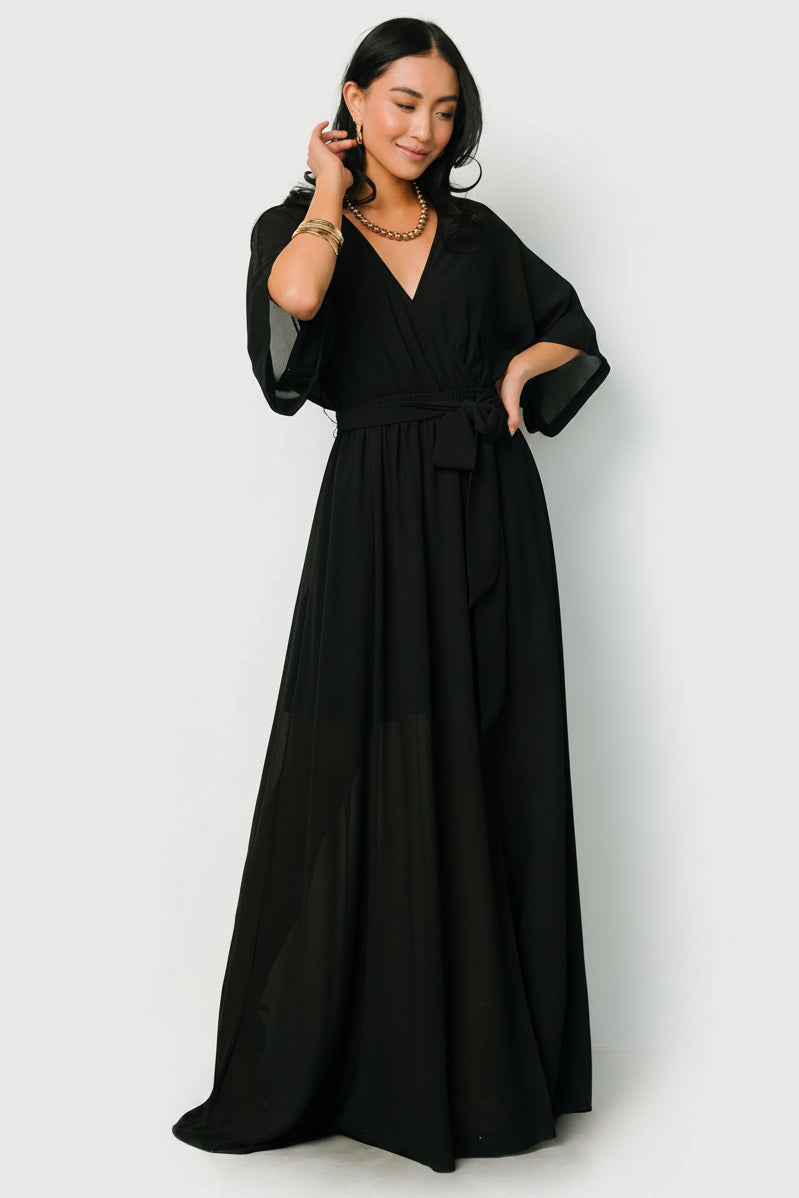 Styled flat-lay of Kia Kimono Maxi Dress in black emphasizing kimono sleeves, detachable sash and maxi hemline proportions.