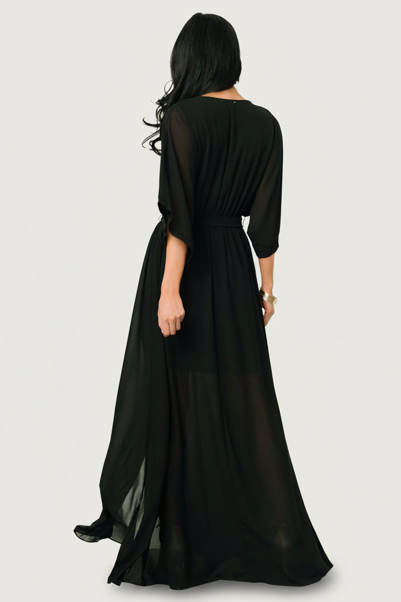 Side view of Kia Kimono Maxi Dress in black with left-side leg slit visible and skirt movement while standing.