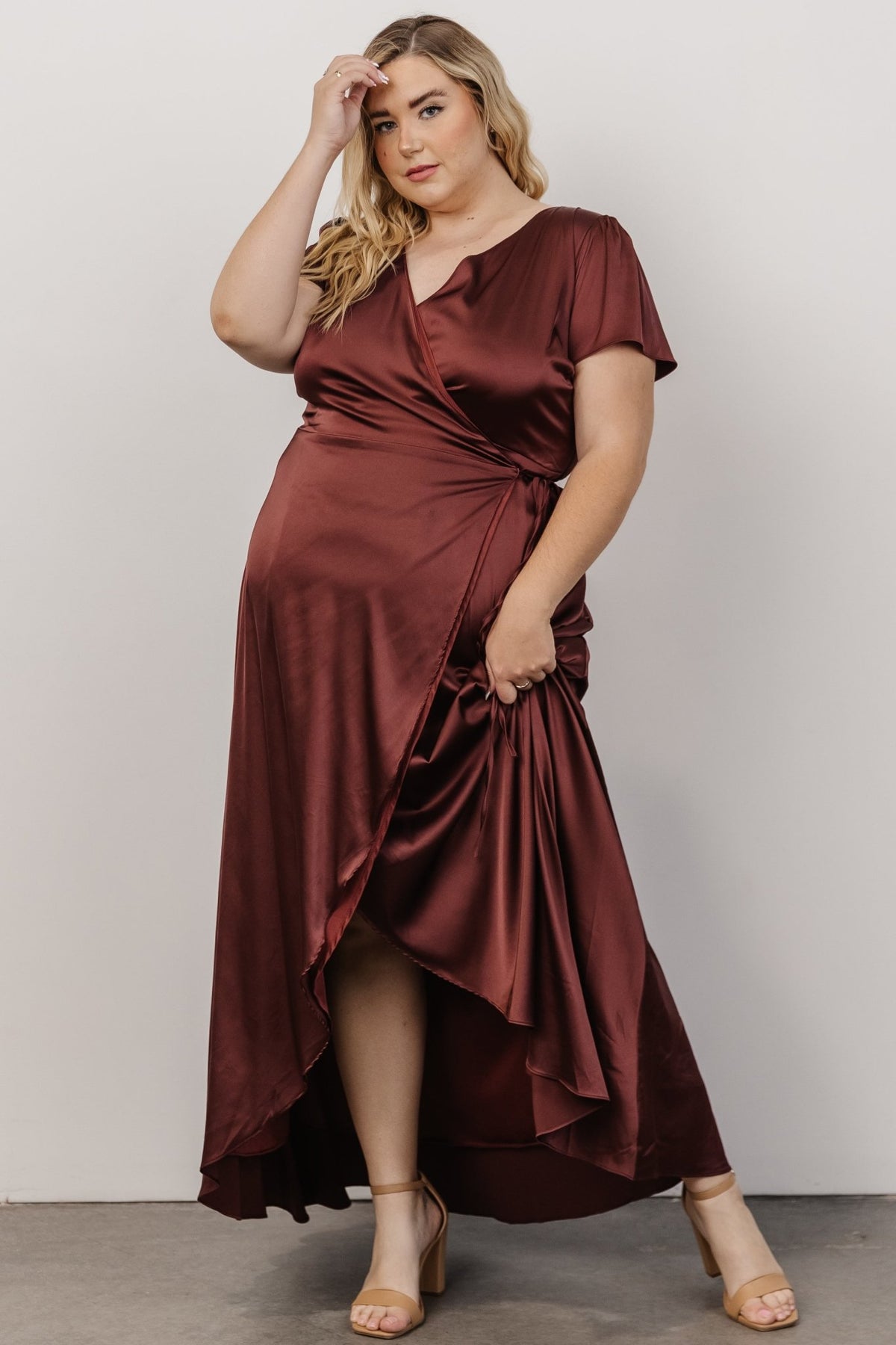 Styled shot of Krystal Satin Wrap Gown in dark clove paired with heels, showing overall silhouette, V-neckline and elegant evening styling.